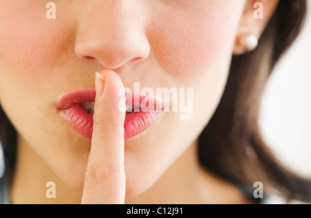 Junge Frau mit Finger auf Lippen, Nahaufnahme Stockfoto