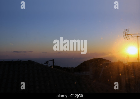 Sonnenuntergang Licht reflektiert durch gefärbten Fensterglas und über Dorf Dächer. Stockfoto