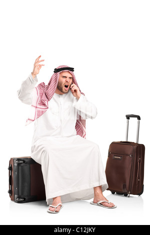 Ein wütend arabische Geschrei auf dem Handy sitzt auf seinem Gepäck Stockfoto