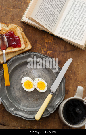 Gekochten Eiern und Toast auf Tisch mit Buch Stockfoto