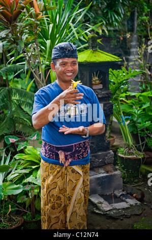 Ein Hindu Mann in traditioneller Kleidung betet an seine Familie Tempel für die Reinigung und eine spezielle klingelt für zeremonielle Zwecke. Stockfoto