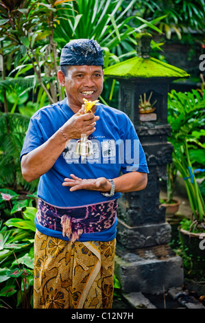 Ein Hindu Mann in traditioneller Kleidung betet an seine Familie Tempel für die Reinigung und eine spezielle klingelt für zeremonielle Zwecke. Stockfoto