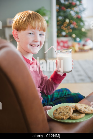 Porträt des jungen (8-9) halten Milch und Kekse am Heiligabend, Jersey City, New Jersey, USA Stockfoto