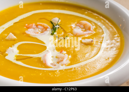 frischer Kürbis und Garnelen-Creme-Suppe mit Sahne obendrauf Stockfoto