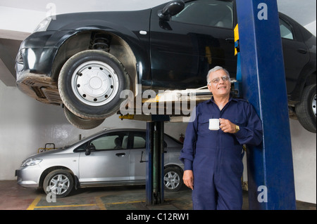 Kfz-Mechaniker hält eine Tasse Kaffee in einer garage Stockfoto