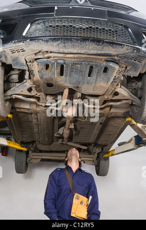 Kfz-Mechaniker arbeiten unter einem erhöhten Auto in einer garage Stockfoto
