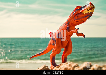 Spielzeug Dinosaurier am Strand Stockfoto