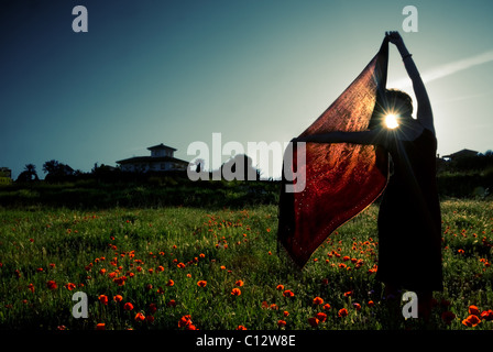 Frau hält roten Schal in Bereich der Wildblumen, Sonnenuntergang, Granada, Andalusien Stockfoto