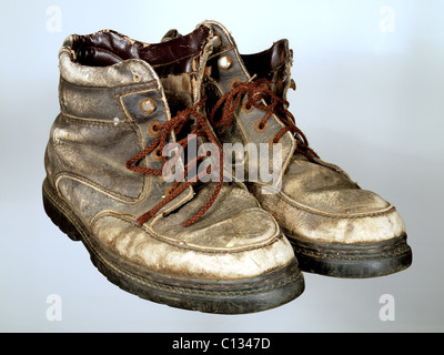 Das alte, abgenutzte Stiefel mit braunen Schnürsenkeln auf einen neutralen Hintergrund. Stockfoto