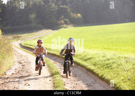 Zwei junge Kinder Reiten Fahrräder im park Stockfoto