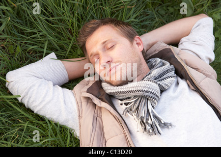 Junger Mann allein ein Nickerchen auf dem Rasen Stockfoto