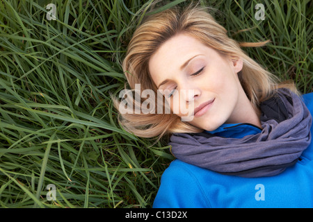 Junge Frau, die allein auf dem Rasen ein Nickerchen Stockfoto