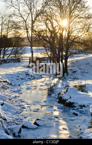 Kleiner Bach oder Verbrennung von Feld und Tor im tiefen Winter mit Sonnenuntergang Stockfoto
