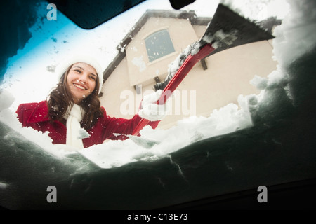USA, Utah, Lehi, junge Frau Schnee vom Auto Windschutzscheibe kratzen Stockfoto