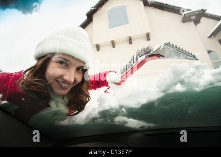USA, Utah, Lehi, Porträt der jungen Frau Schnee vom Auto Windschutzscheibe kratzen Stockfoto