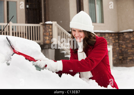 USA, Utah, Lehi, junge Frau, die Schaben Schnee vom Auto Stockfoto