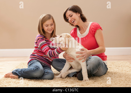 USA, Utah, Lehi, Mutter und Tochter (10-11) spielen mit Labrador auf Teppich Stockfoto