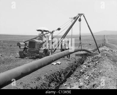 Fallen einem geschweißten Rohr in einen Graben mit einem Kran beim Verlegen der Rohrleitung der Iraq Petroleum Company in ganz Palästina die Ebene von Esdraelon, Juli 1933. Abgeschlossen im Jahr 1934, lief die Pipeline von Kirkuk, Al Hadithah (jetzt NW Saudi-Arabien), dann Verzweigung mit Pipelines nach Tripolis und Haifa. Stockfoto