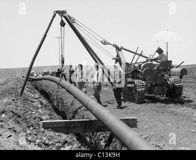 Fallen einem geschweißten Rohr in einen Graben mit einem Kran beim Verlegen der Rohrleitung der Iraq Petroleum Company in ganz Palästina die Ebene von Esdraelon, Juli 1933. Abgeschlossen im Jahr 1934, lief die Pipeline von Kirkuk, Al Hadithah (jetzt NW Saudi-Arabien), dann Verzweigung mit Pipelines nach Tripolis und Haifa. Stockfoto