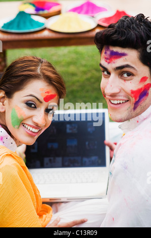 Porträt von ein paar mit einem Laptop auf Holi Stockfoto