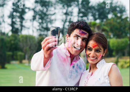 Paar, ein Bild von sich selbst mit einem Mobiltelefon am Holi Stockfoto