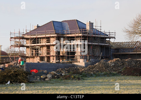 Gerüst auf ein großes neues Haus auf der grünen Wiese errichtet. Wales, UK, Großbritannien, Europa. Stockfoto