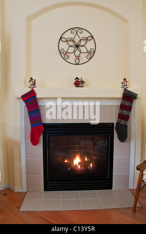 Diese innere vertikale Bild zeigt eine Wand mit einem niedlichen Alkoven und ein Feuer in einem Gaskamin mit Weihnachtsstrümpfe gehen Stockfoto