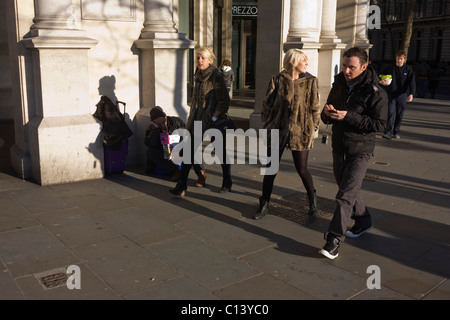 Ein schlafender Big Issue Magazin Verkäufer sitzt alleine ohne Geschäft als desinteressiert auf Zuschauer Pass-by in London übergeben. Stockfoto