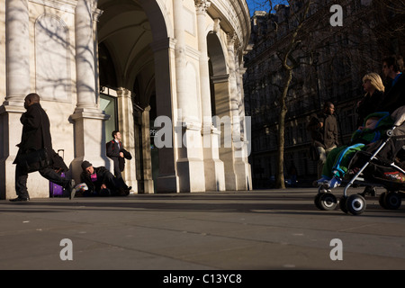 Ein schlafender Big Issue Magazin Verkäufer sitzt alleine ohne Geschäft als desinteressiert auf Zuschauer Pass-by in London übergeben. Stockfoto