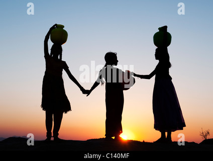 Indische Bauerndorf Mädchen mit Wasser Töpfe bei Sonnenuntergang. Silhouette. Andhra Pradesh, Indien Stockfoto