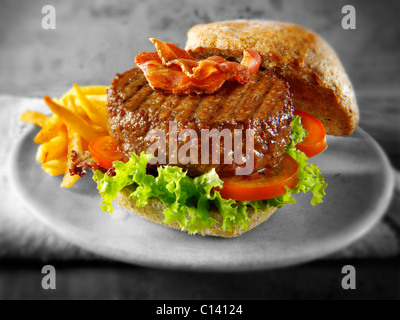 Rindfleisch-Burger mit Speck in einem Vollkorn Brötchen mit Salat und Pommes frites Stockfoto