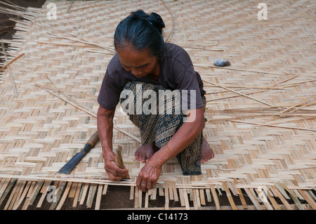 Frau weben Split Bambus in traditionellen Platten an den Wänden und Decke der traditionellen balinesischen Häuser Stockfoto