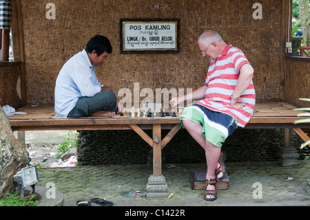 Ältere Touriust ein freundliches Spiel Schach mit einem Einheimischen in Ubud, Bali, Indonesien Stockfoto