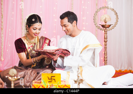 Bräutigam der Braut bei der Süd-indischen Hochzeit Zeremonie einen Sari verleihen Stockfoto