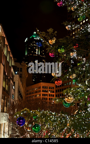 Dieses vertikale Bild ist Seattle, Washington downtown in der Nacht während der Weihnachtszeit. Ein riesiger geschmückter Weihnachtsbaum. Stockfoto