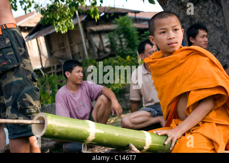 Ein junger Mönch sitzt auf einer Bambus-Rakete, die er für ein Festival in einem Tempel in kommunistische Laos bildet. Stockfoto