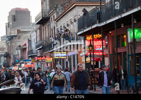 Menschen kreuzen von Leuchtreklamen an Bars und Nachtclubs auf der Bourbon Street in der Nacht in New Orleans Stockfoto