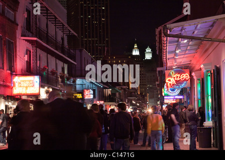 Menschen, die entlang der Bourbon Street in New Orleans mit Leuchtreklamen in der Nacht Stockfoto