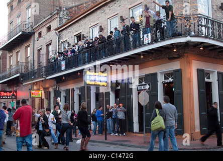 Menschen trinken und tanzen auf der Straße als Leute zu beobachten auf dem Balkon einer Bourbon Street Bar in New Orleans Stockfoto