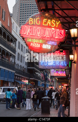 Menschen zu Fuß durch Neon-Schilder für Bars und Clubs entlang der Bourbon Street in New Orleans in der Nacht Stockfoto