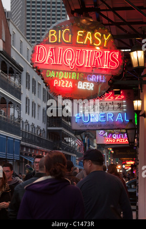 Menschen, die nachts unter Leuchtreklamen für Bars und Clubs entlang der Bourbon Street in New Orleans Stockfoto