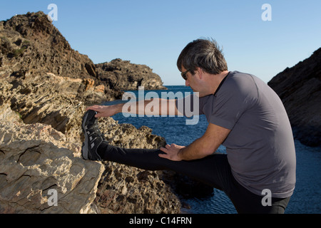 Mann, erstreckt sich auf einer felsigen Küste in Spanien Stockfoto