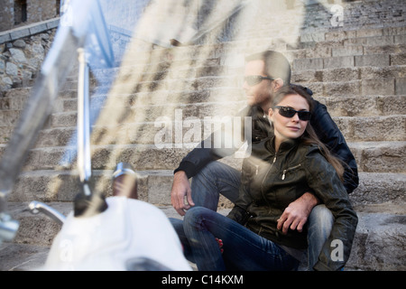 Paar Umarmung auf Schritte neben Motorroller, Blick durch das Visier Stockfoto