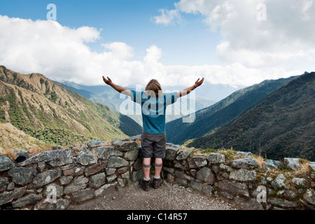 Ein junger Mann breitet seine Arme in die Landschaft in den Anden entlang des Inka-Trail zu. Stockfoto