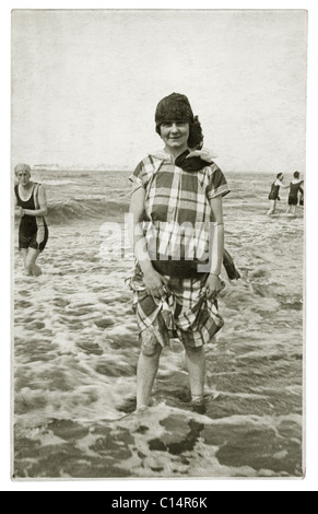 Ursprüngliche Postkarte aus der Zeit der 1920er Jahre mit einer jungen Frau in Freizeitkleidung, die im Meer paddelt - Zeitvertreibe Anfang der 1920er Jahre, britisches Retro-Strandfoto. Stockfoto