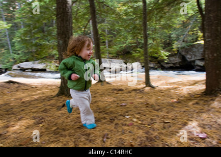 Ein junges Mädchen läuft durch den Wald. Stockfoto