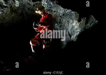 Ein Bergmann untersuchen Felsen im Süden Crofty Tin Mine, Cornwall. Stockfoto