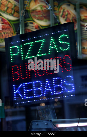 Take-Away Pizza, Burger, Döner Zeichen und Logos in einem Schaufenster in Hove, East Sussex, UK. Stockfoto