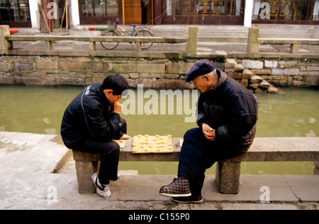 Qibao Lau, China. Großvater und Enkel spielen Halma am Kanal in der Altstadt in der Nähe von Shanghai.  © Bob Kreisel Stockfoto