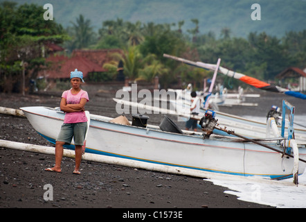 Eine balinesische Frau wartet am Strand für ihren Ehemännern Fischerboot zu kommen nach Nächten Angeln auf Makrele in Amed, Bali Stockfoto